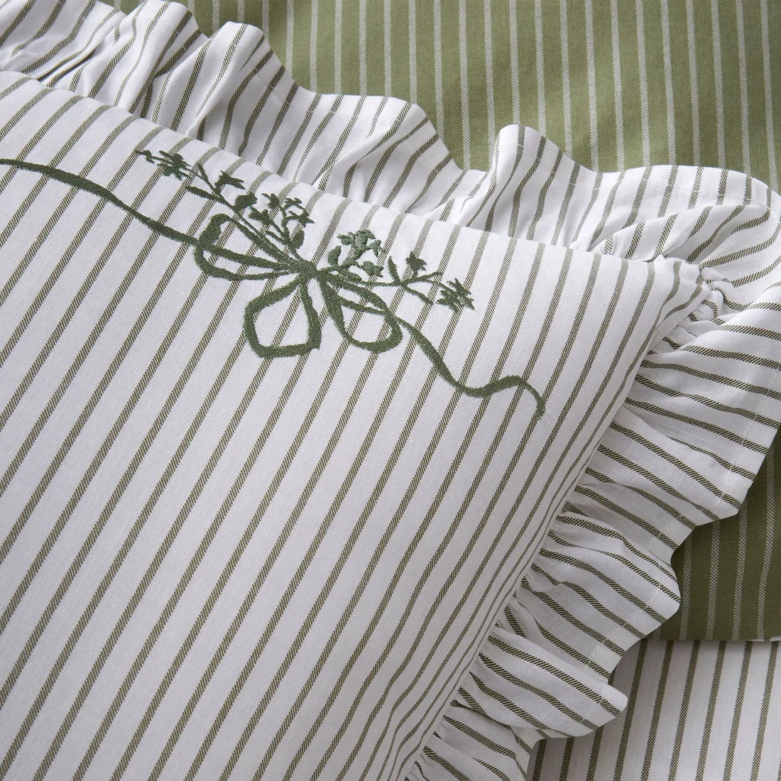 Close-up of the embroidered olive green bows on the Appletree Frilled Embroidered Bow Stripe pillowcases.