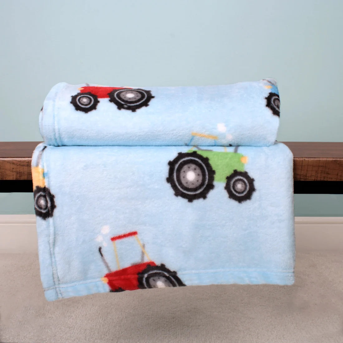 Bedlam Farmyard Friends reversible fleece throw in blue featuring colourful tractors.