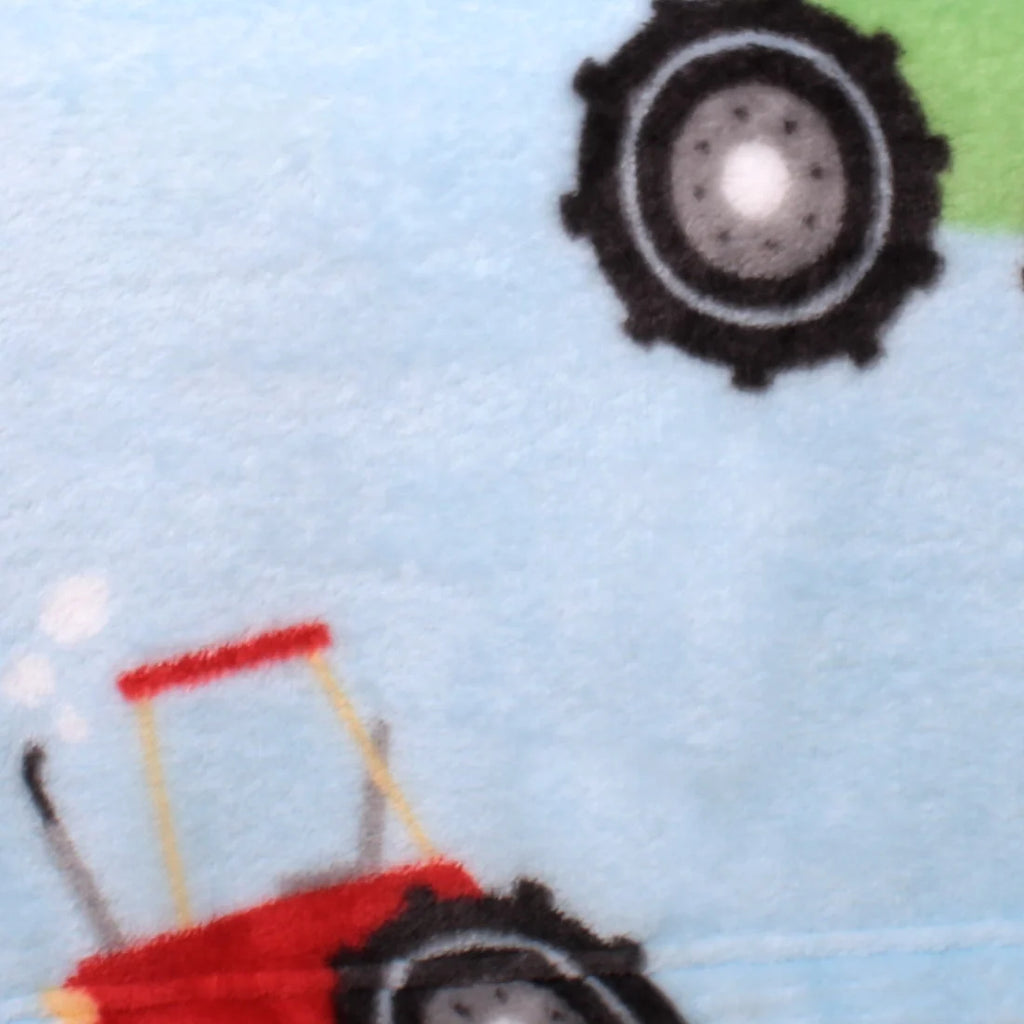 A close-up of a light blue fabric with a printed pattern of red tractors and black wheels.