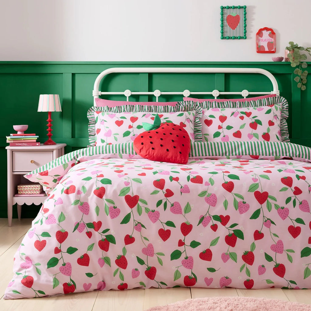 Bedroom with strawberry-themed bedding and green wall.