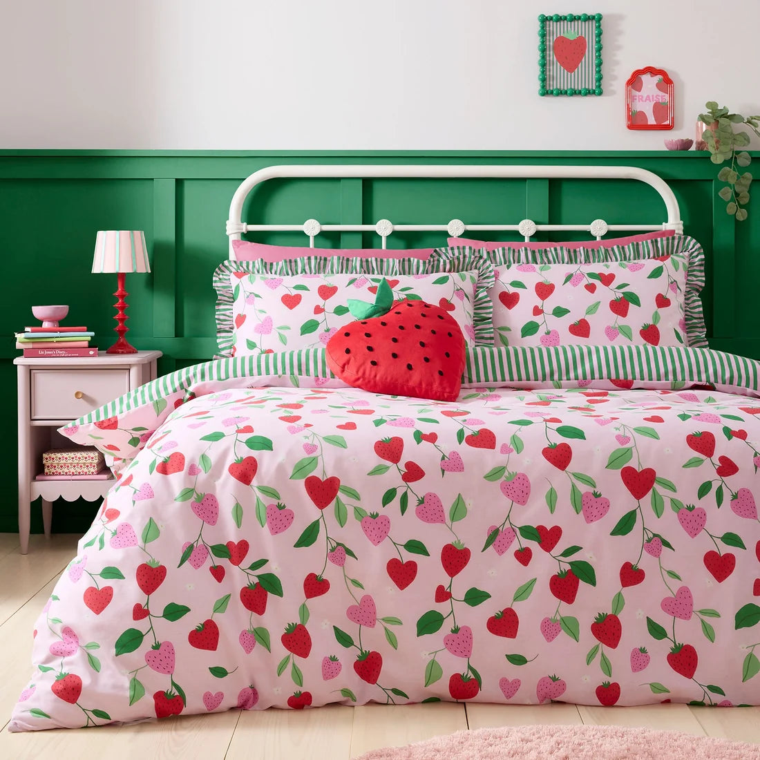 Bedroom with strawberry-themed bedding and green wall.
