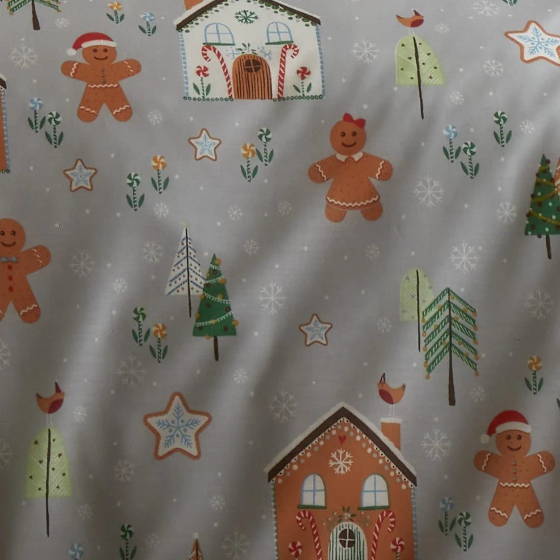 Christmas-themed fabric with gingerbread men, houses, trees, and snowflakes on a gray background.