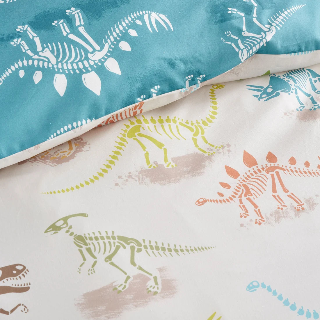 Children's bedding with dinosaur skeleton patterns on a blue and white background