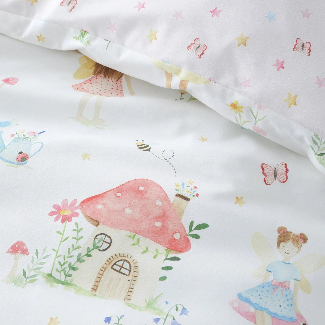 White children's bedding set featuring a whimsical fairy and mushroom house print, with a matching pillowcase visible at the top.