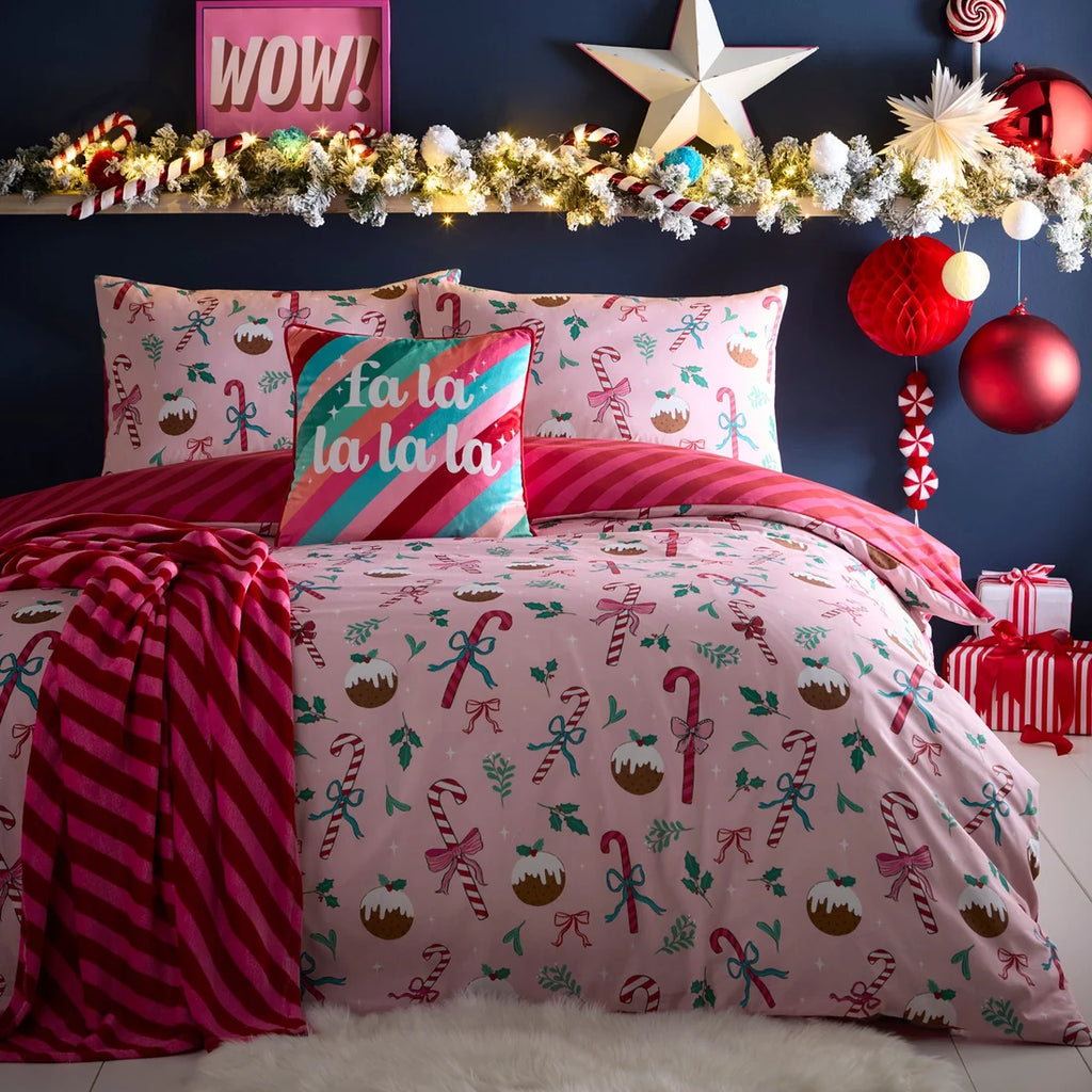 Decorative Christmas-themed bedding set with festive pillows and a garland on a bed.