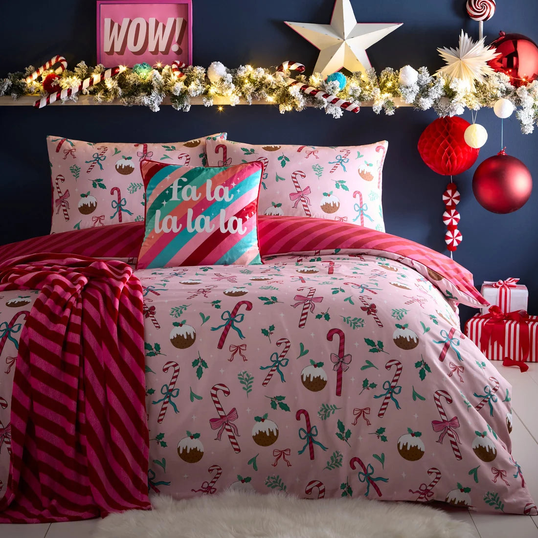 Decorative Christmas-themed bedding set with festive pillows and a garland on a bed.