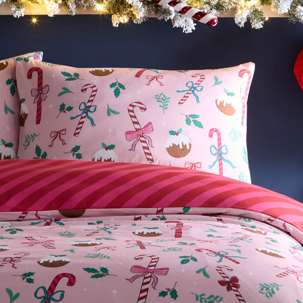 Christmas-themed bedding set with candy canes, bows, and gingerbread men on a pink background.