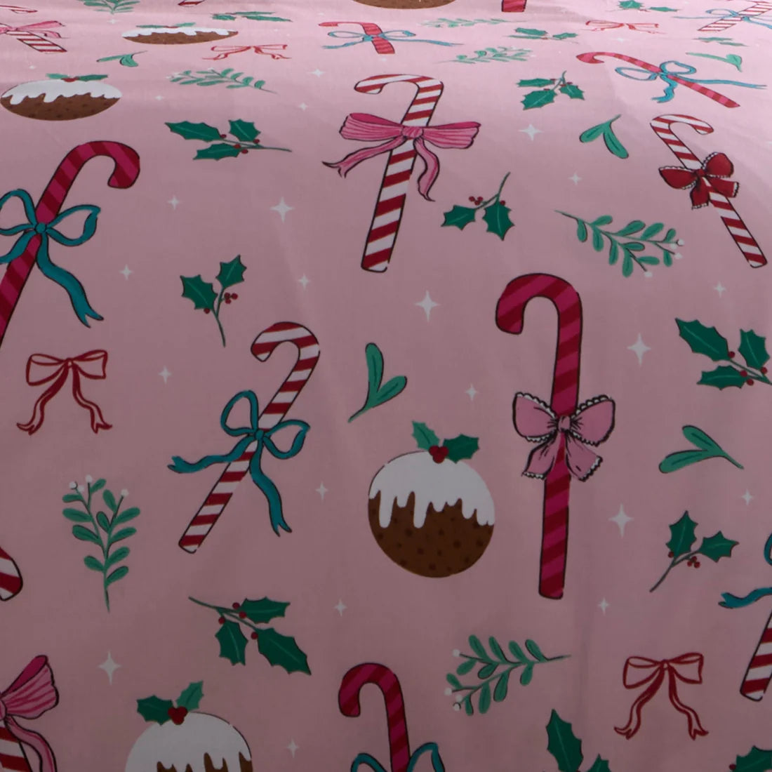 Pink fabric with a Christmas print featuring candy canes, holly leaves, bows, and a pudding.