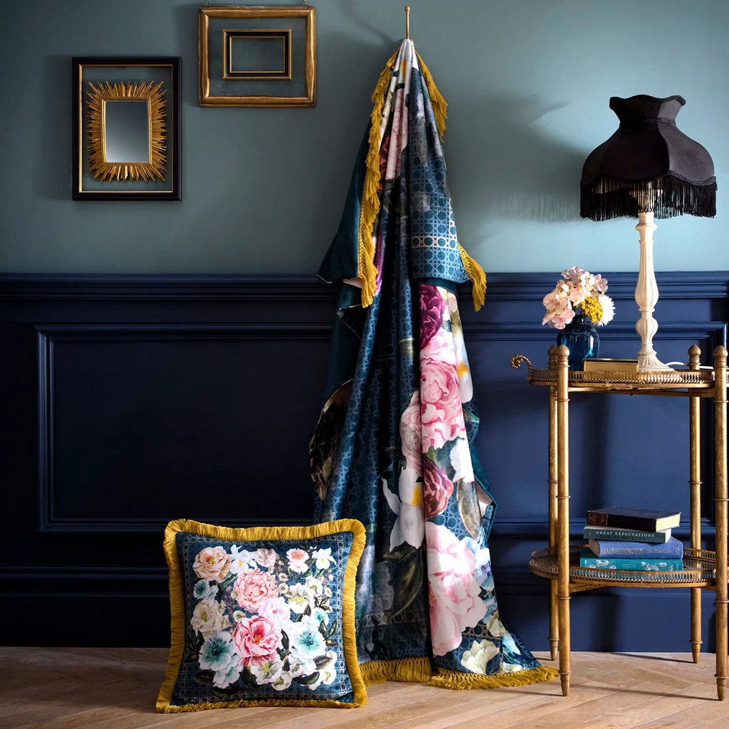 Floral-patterned blanket and pillow on a wooden floor against a blue wall with decorative elements.
