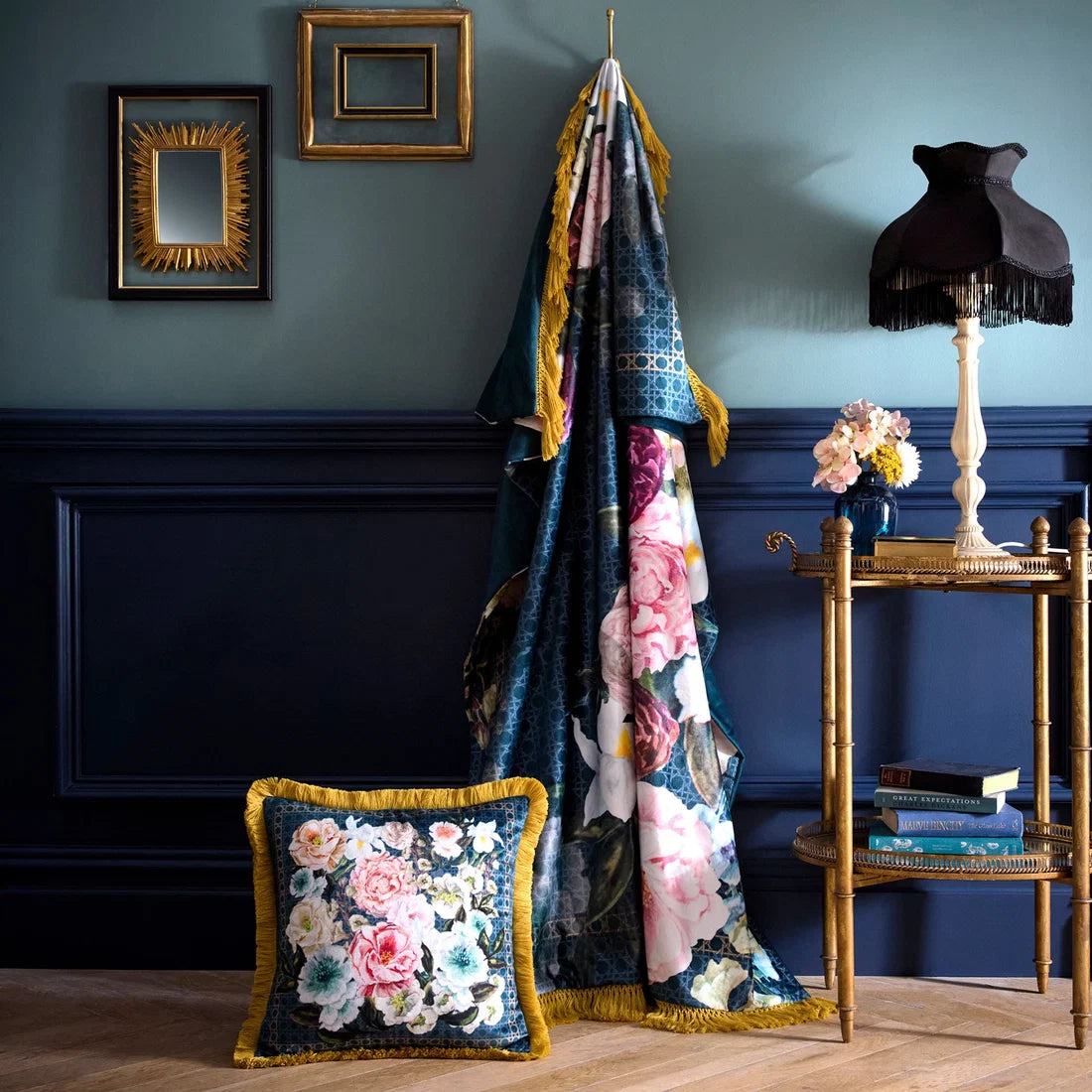 Floral-patterned blanket and pillow on a wooden floor against a blue wall with decorative elements.