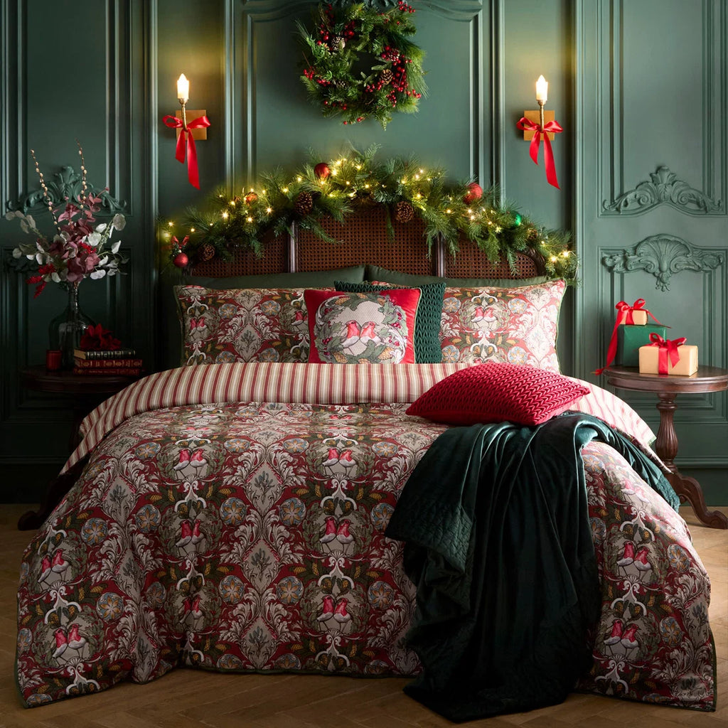 Laurence Llewelyn-Bowen Festive Robin red velvet cushion styled on a luxury festive bed