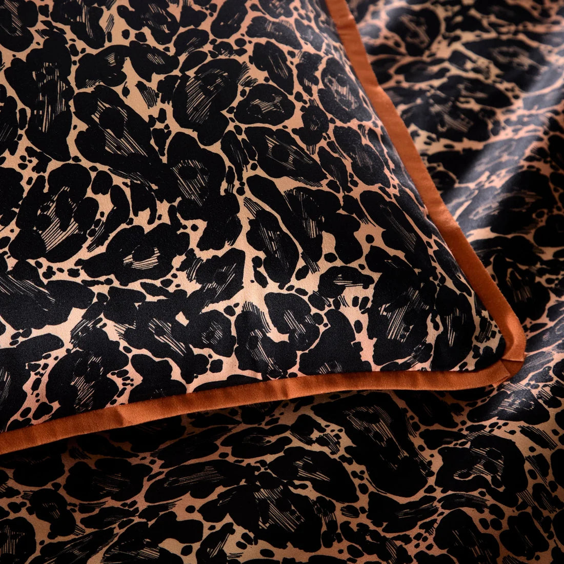 Close-up of the smooth 100% cotton sateen fabric and flat piped edging on the Roxy Leopard duvet cover set.