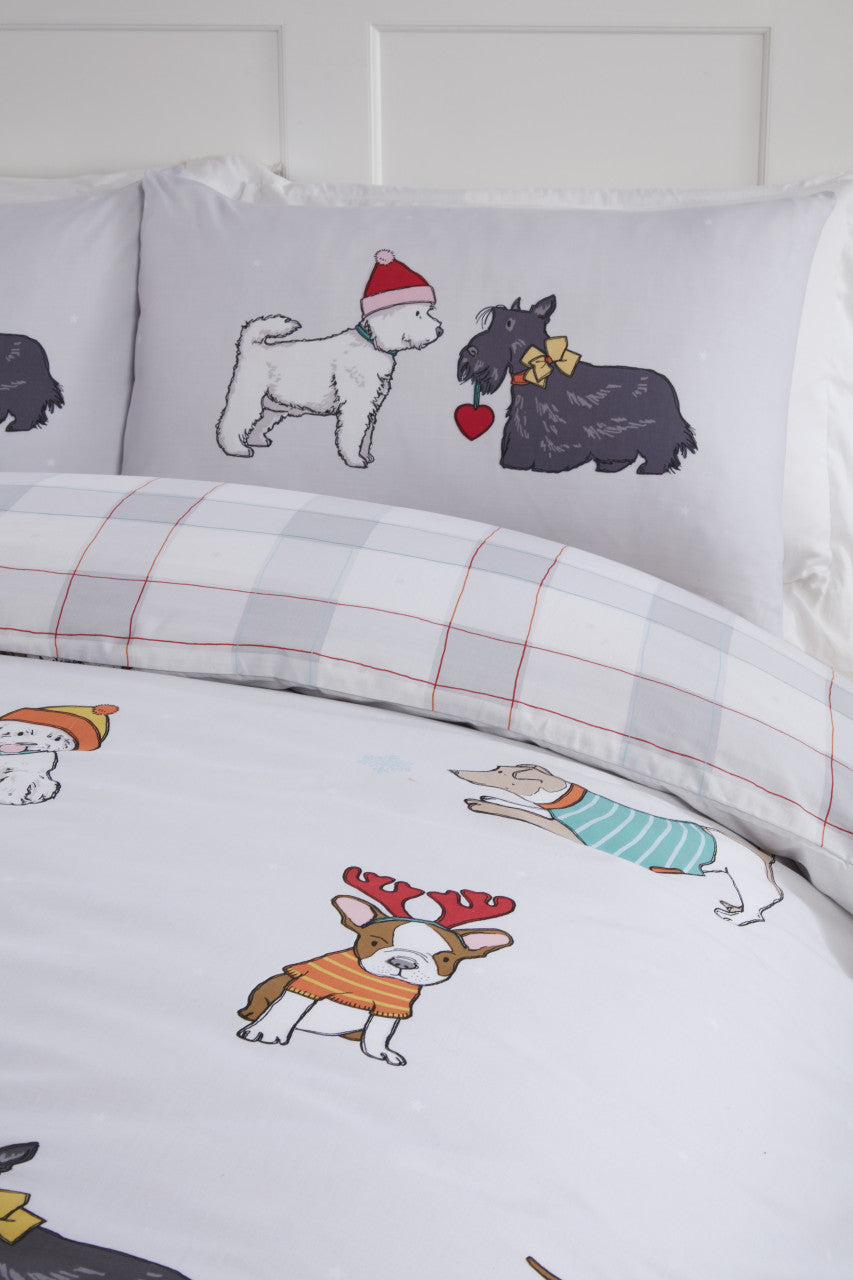 Close-up of the festive dog design wearing Christmas jumpers, hats and scarves on the Winter Tails duvet cover set.